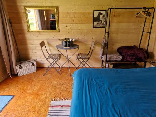 Cette chambre comprend une table, des chaises et un miroir. dans l'établissement La cabane des lucioles, à Saint-Julien-Boutières
