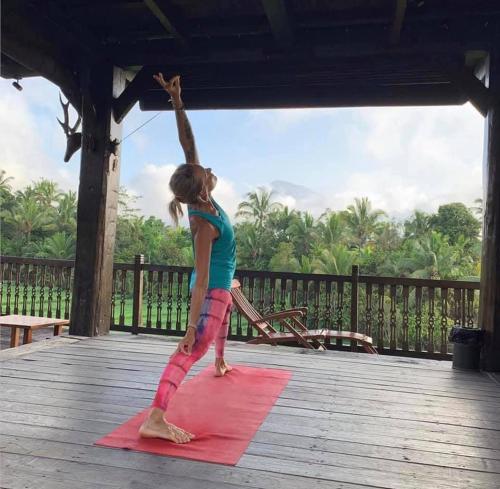 a little girl doing a yoga pose on a red mat at The Ravaya Arim Villa -Peaceful, Romantic, Natural in Blimbing