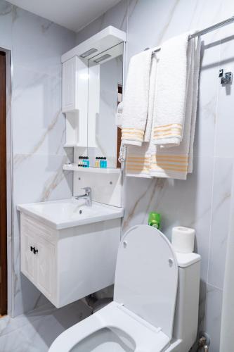 a white bathroom with a toilet and a sink at Meros Boutique Hotel in Samarkand