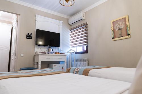 a hotel room with two beds and a flat screen tv at Meros Boutique Hotel in Samarkand