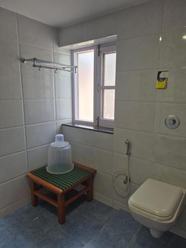 a bathroom with a toilet and a window and a table at The Green Mountain Lodge in Manāli