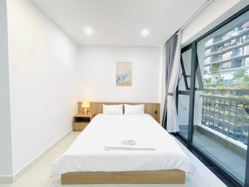 a bedroom with a white bed and a large window at 501 Modern Studio with Balcony & Kitchen in Ho Chi Minh City