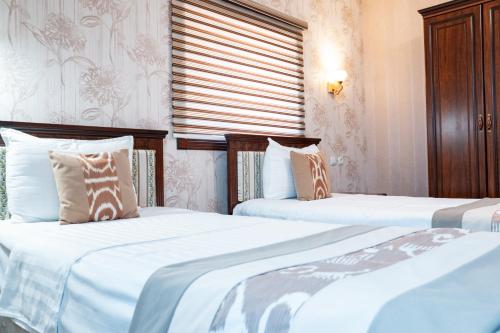 two beds in a hotel room with white sheets at Meros Boutique Hotel in Samarkand