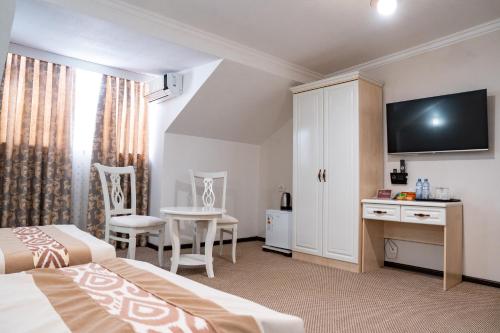 a bedroom with two beds and a table and a tv at Meros Boutique Hotel in Samarkand