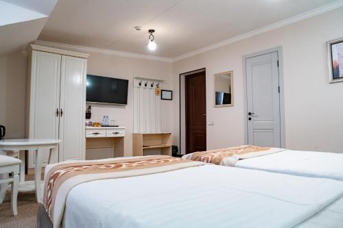 two beds in a room with a desk and a table at Meros Boutique Hotel in Samarkand