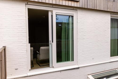 a sliding glass door with a chair in a house at VlieMare Appartementen De Kluut in Oost-Vlieland