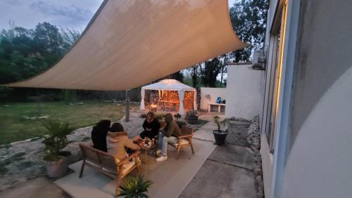 un groupe de personnes assises sur une terrasse sous une tente dans l'établissement Le Clos des Oiseaux YourHostHelper, à Narbonne