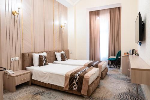 a hotel room with two beds and a television at Meros Boutique Hotel in Samarkand