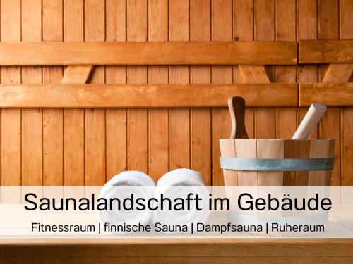 a sauna with a wooden wall and a wooden spoon at Ostsee-Traumferienwohnungen Bel Vital mit Meerblick, Balkon und Sauna in Binz