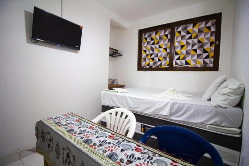 a room with two beds and a table and a tv at Flat inteiro 100m 1 Praia -Morro de Sao Paulo Bahia- mare mansa c in Cayru