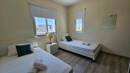 two beds in a room with two windows at Kyma 3 Bed Villa + Pool in Paphos