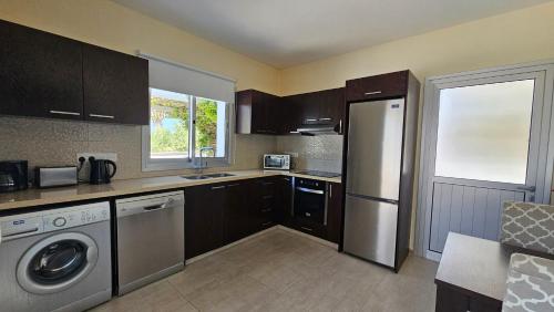 a kitchen with a refrigerator and a washer and dryer at Kyma 3 Bed Villa + Pool in Paphos