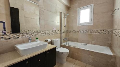 a bathroom with a sink and a toilet and a tub at Kyma 3 Bed Villa + Pool in Paphos