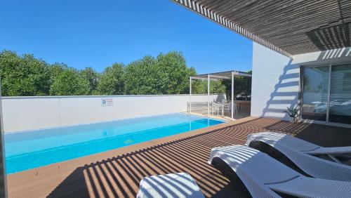 a swimming pool with blue chairs on a deck at Kyma 3 Bed Villa + Pool in Paphos