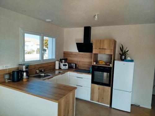 une cuisine avec un réfrigérateur blanc et un évier dans l'établissement Ladybird Maison 4 à 5 pers climatisée, à Longeville-sur-Mer