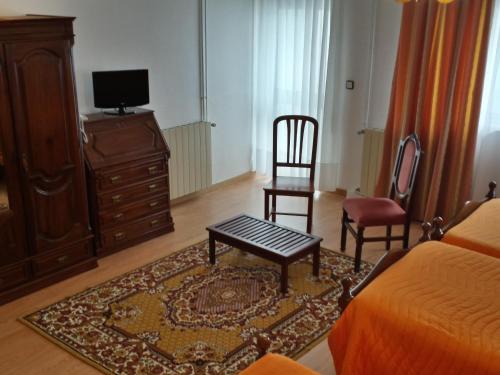 a bedroom with a bed and two chairs and a tv at Pensao Vista Bela in Miranda do Douro