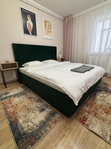 a bedroom with a large bed in a room with rugs at Studio Central in Onești