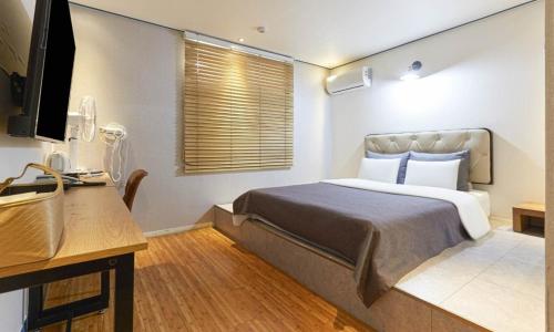 a bedroom with a bed and a desk and a television at Chuncheon Urbane Hotel in Chuncheon