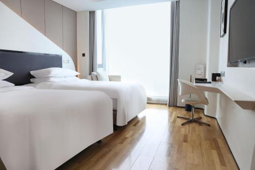 a hotel room with two beds and a desk at FlyZoo Hotel - Alibaba Future Hotel in Hangzhou