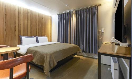 a hotel room with a bed and a table and a table at Chuncheon Urbane Hotel in Chuncheon