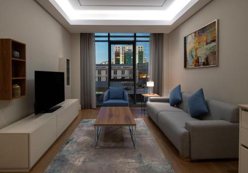 a living room with a couch and a tv at Movenpick Living Istanbul West in Istanbul