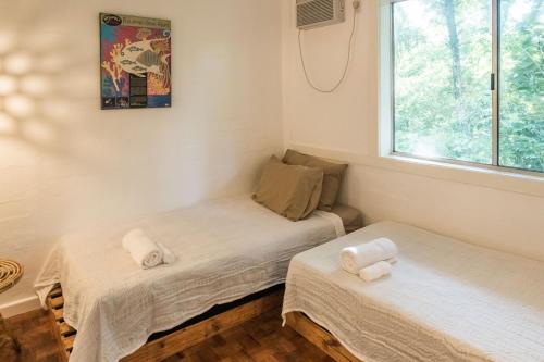 two twin beds in a room with a window at Rainforest Nest - CAHAYA, PITI, VIRYA Nest with Self-Service Breakfast, Balcony, Monkeys, Bats! in Subic Bay Intl