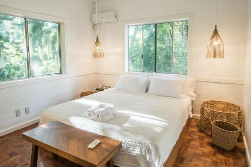 a bedroom with a bed with a table and windows at Rainforest Nest - CAHAYA, PITI, VIRYA Nest with Self-Service Breakfast, Balcony, Monkeys, Bats! in Subic Bay Intl
