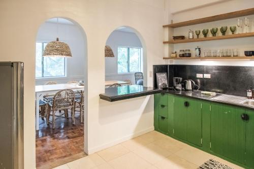 a kitchen with green cabinets and a dining room at Rainforest Nest - CAHAYA, PITI, VIRYA Nest with Self-Service Breakfast, Balcony, Monkeys, Bats! in Subic Bay Intl