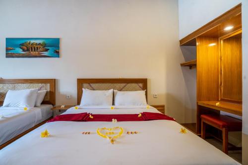 a bedroom with two beds with a heart decoration on it at Rumah Gajah by Kubukubali in Pemuteran