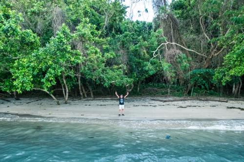 a person standing on a beach with their arms in the air at Rainforest Nest - CAHAYA, PITI, VIRYA Nest with Self-Service Breakfast, Balcony, Monkeys, Bats! in Subic Bay Intl