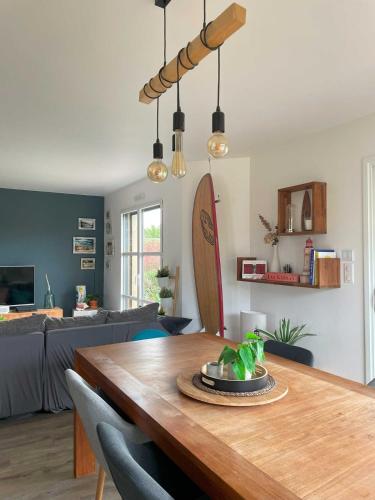 un salon avec une table en bois et une planche de surf dans l'établissement Maison de vacances Loctudy, à Loctudy