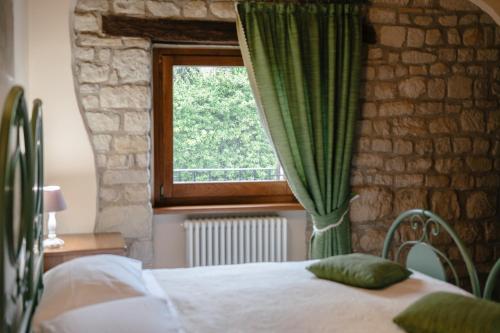 a bedroom with a bed and a window with green curtains at Le Fontanelle Country House in SantʼIppolito