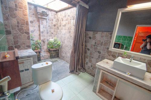 a bathroom with a toilet and a sink and a mirror at Rumah Gajah by Kubukubali in Pemuteran