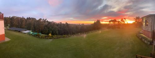 a sunset over a green yard with trees and a building at House with a View in Groot Brak Rivier