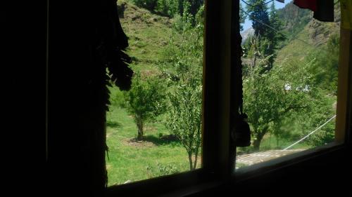 a window looking out at a field of trees at The Sigiriya Old manali in Manāli