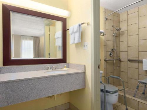 a bathroom with a sink and a toilet and a mirror at Days Inn by Wyndham Brunswick/St. Simons Area in Glynn Heights