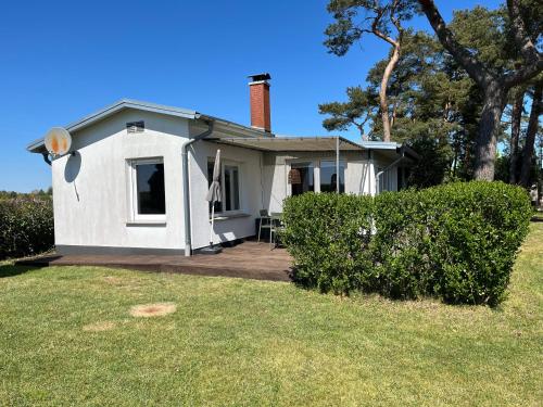 a small white house with a porch and a lawn at Ferienhaus Solken mit großer Terrasse und Kaminofen in Plau am See
