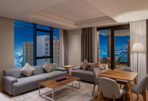 a living room with a couch and tables and windows at Movenpick Living Istanbul West in Istanbul