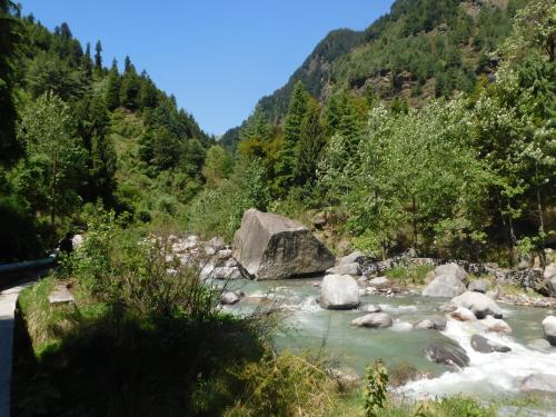 a river with rocks in the middle of a mountain at The Sigiriya Old manali in Manāli