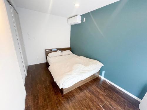 a small bed in a room with a blue wall at Vamos Villa Tokunosima in Tokunoshima