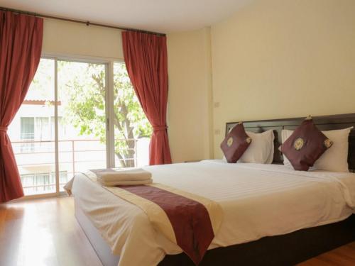 a bedroom with a large bed with red curtains at Kiatthada Resort in Bangkok