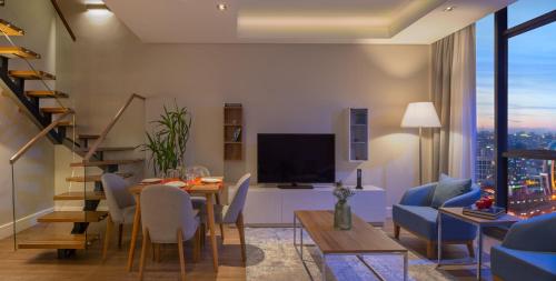a living room with a dining table and a tv at Movenpick Living Istanbul West in Istanbul