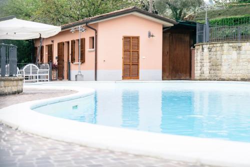 a swimming pool in front of a house at Le Fontanelle Country House in SantʼIppolito