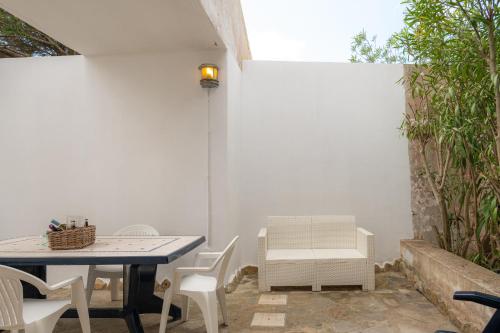 a patio with a table and white chairs at Casa Vacanze - Domus De Mar in Stintino