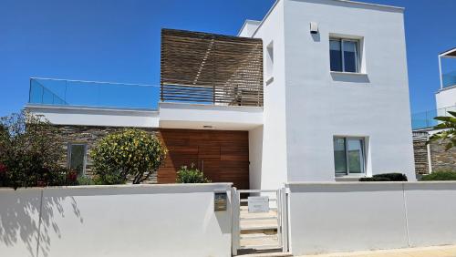 a house with white walls and a fence at Plage Residences in Paphos City