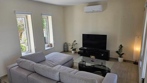 a living room with a couch and a flat screen tv at Plage Residences in Paphos City