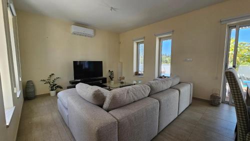 a living room with a couch and a tv at Plage Residences in Paphos City