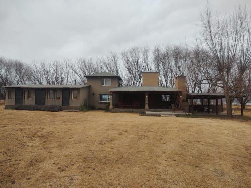 an old house in a field with trees in the background at El descanso tiene nombre propio: Munay in Tafí del Valle