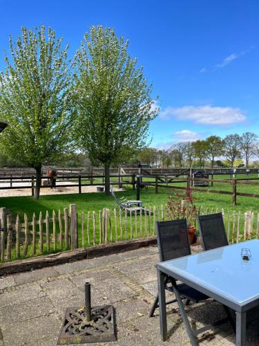 a table and chairs in front of a fence at Linderhuisje, rust, ruimte, privacy en natuur in Linde