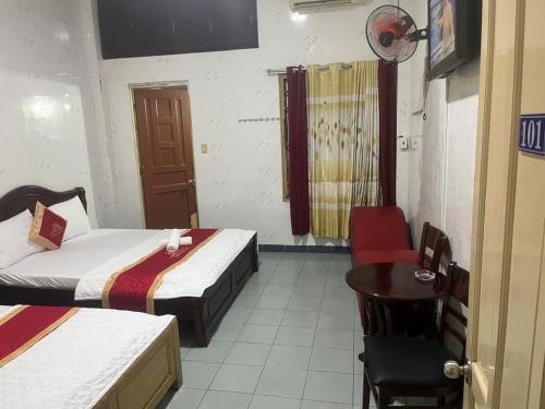 a room with two beds and a table and a chair at Hồng Phát 68 Hotel in Ho Chi Minh City